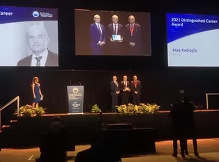Prof. Ateş Kadıoğlu receiving the 2021 Distinguished Career Award on stage at the SIU congress, his name and photograph shown on the screens behind him.